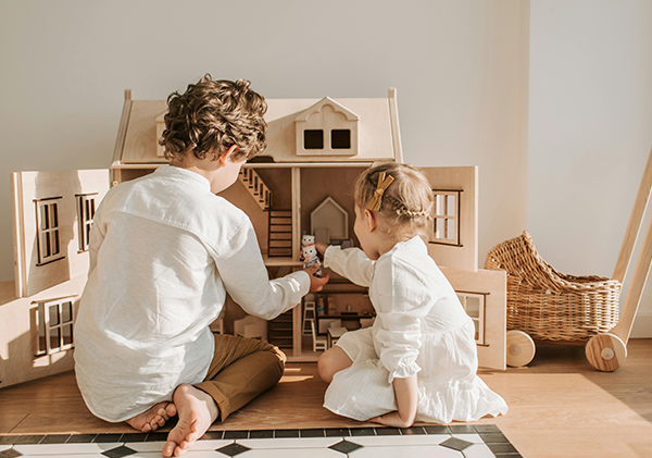 Boy and girl playing together with dolls house