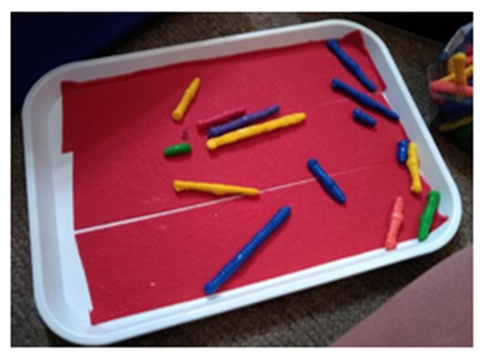 Picture 2 description: A lipped tray with red lining and different length and colour plastic worms on it.