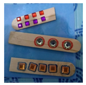 Picture 6 description: Counting sticks made from lolly sticks with plastic gems representing numbers. The gems have a high contrast pen line around them.