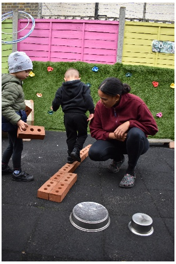 Children balancing on bricks with adult