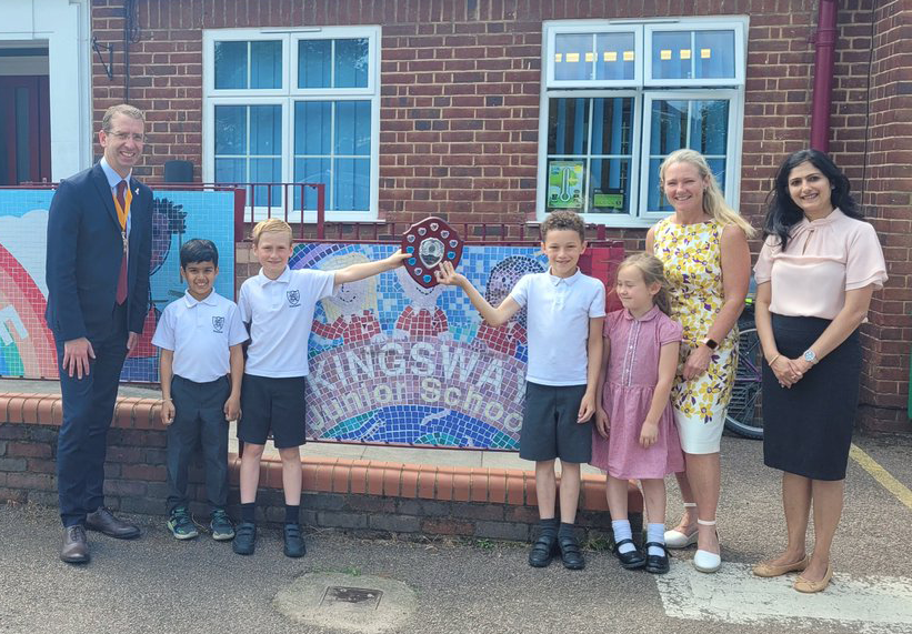 Competition winners posing in front of school with plaque 