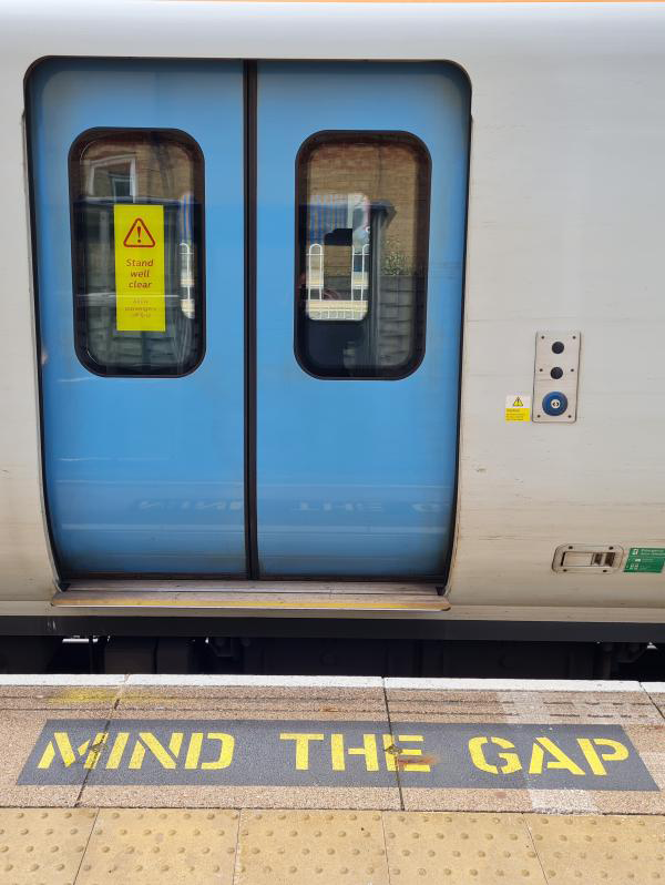 Train doors and sign on platform edge saying "mind the gap"