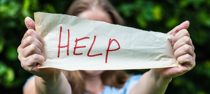 Hands holding up a sign for help