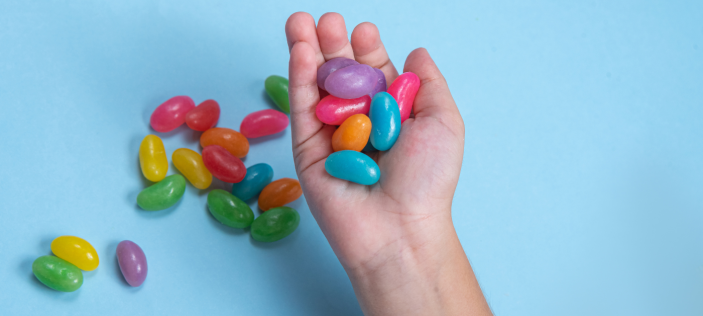 Hand holding large jelly-beans on blue background