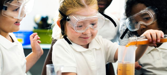 Happy primary age school children conducting science experiments 