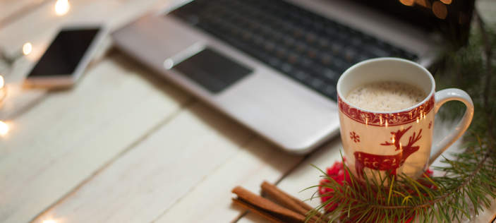 Christmas themed coffee cup in front of laptop