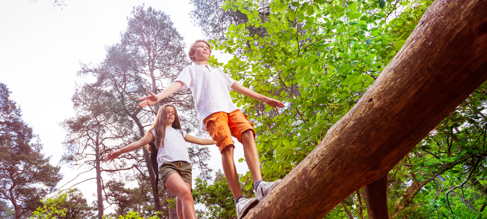 Girl and boy balancing on log