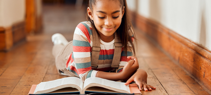 Girl reading book on floor