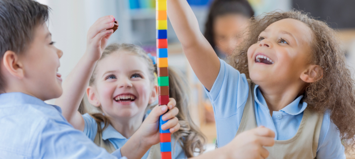 Happy class children building blocks together