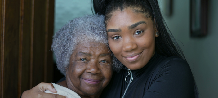 Younger person holding an older person both of African heritage 