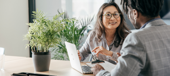 People dressed smartly in conversation with one another. A potted plant is on a desk