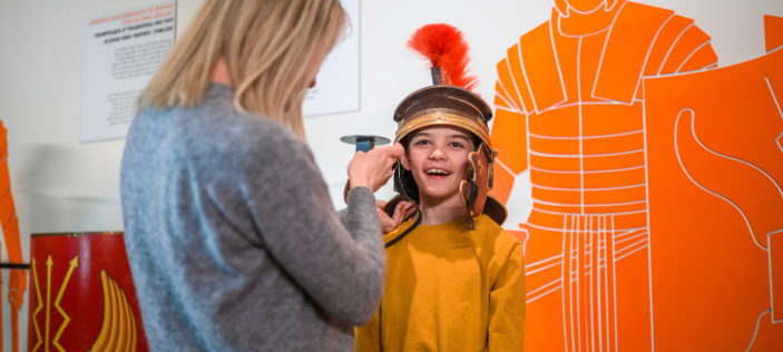Child being fitted out with a Roman helmet