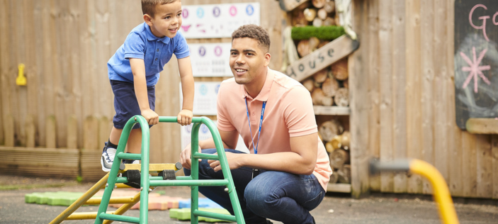 Early Years child on climbing apparatus with adult in attendance 