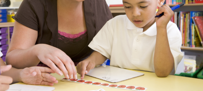 Child with adult at desk