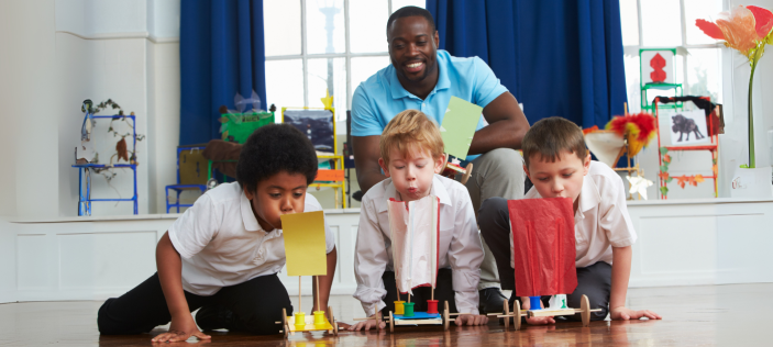 Adult with children blowing on coloured paper