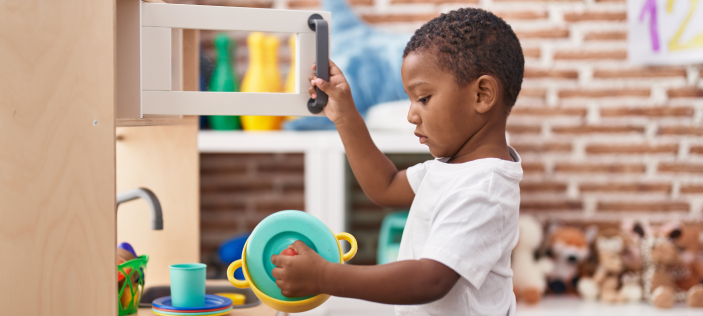 Child playing with a toy microwave and pot