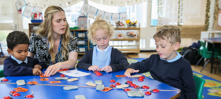 Teacher with Early Years children round blue table