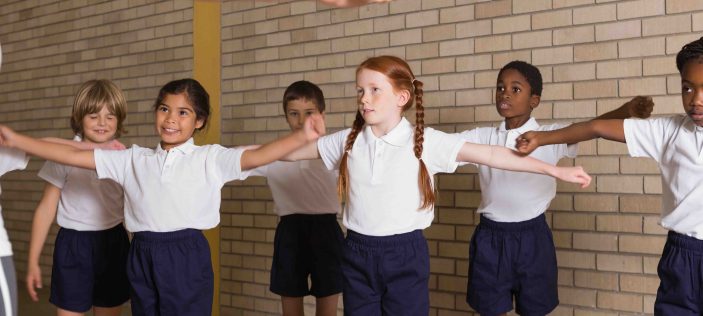 School children with arms out stretched to the side