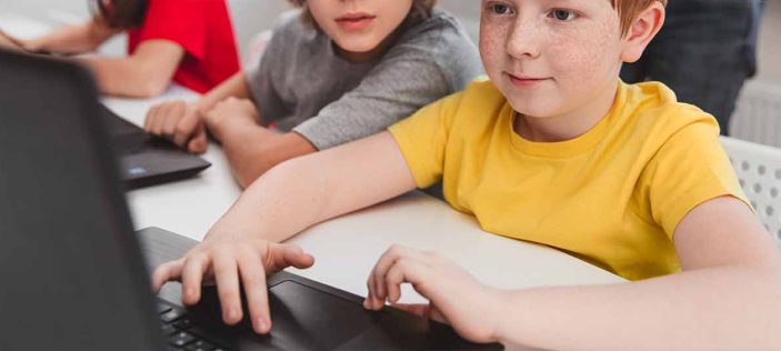 boy in yellow shirt using computer