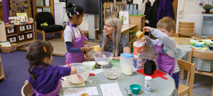 Adult with Early Years children sat round a table 