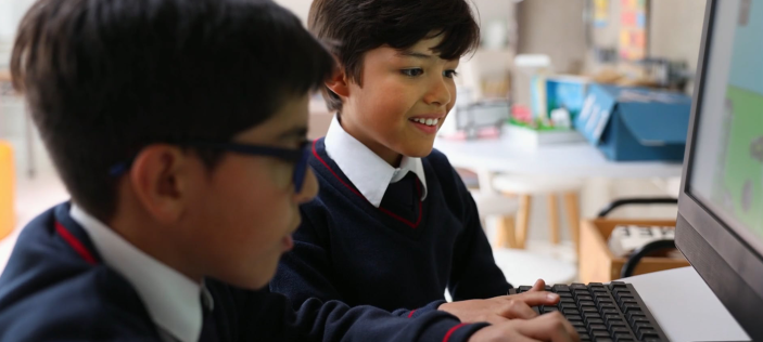 Two children in uniform looking at a computer monitor