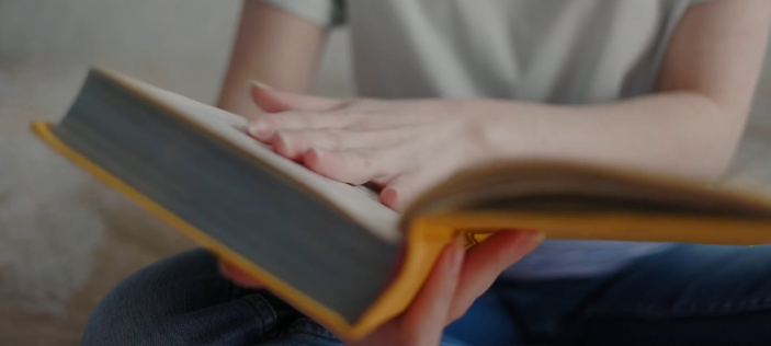 Hand on open yellow book