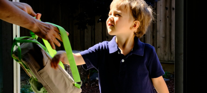 Child putting on a back pack