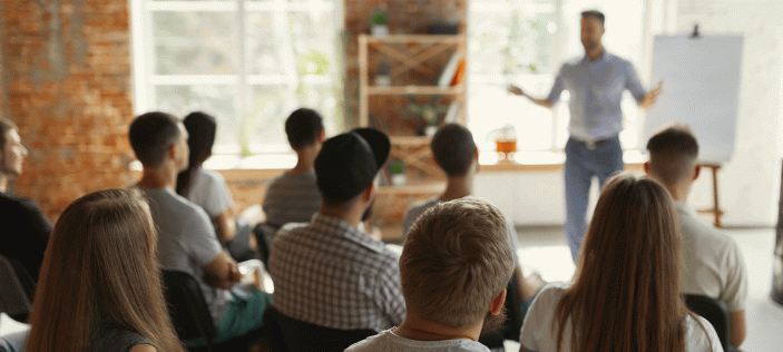 Adult talking to a room of seated adults