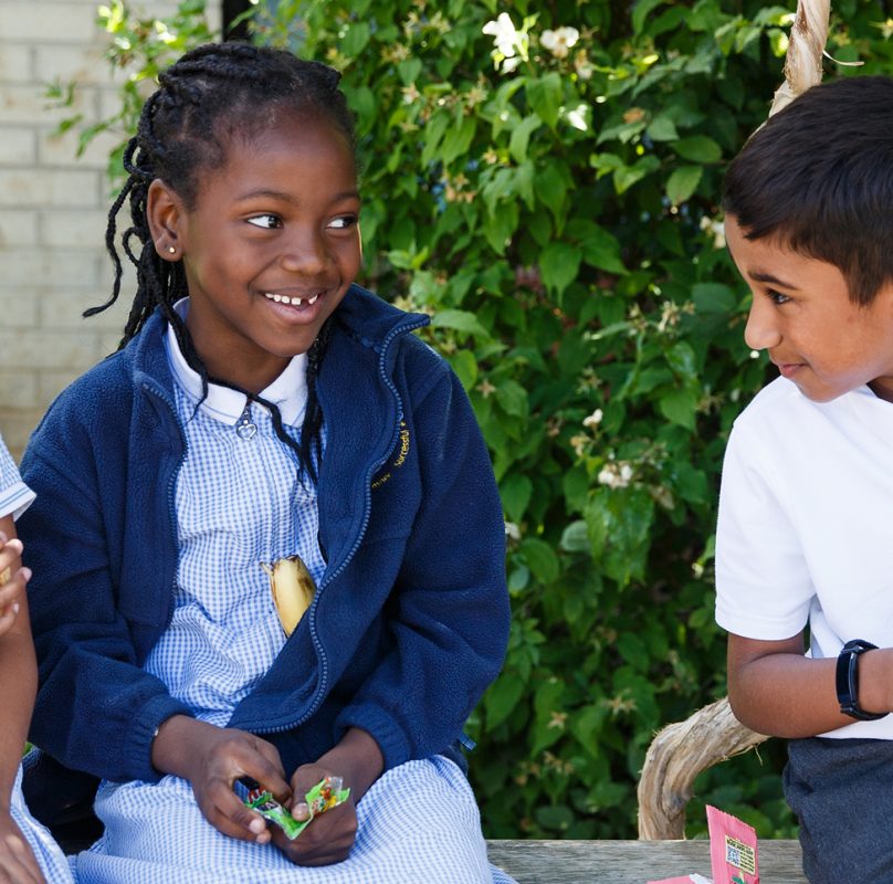 2 girls and a boy on a bench outside