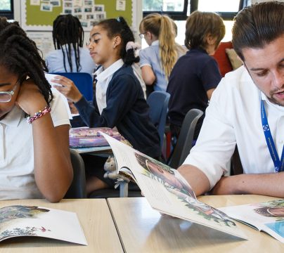 two teachers sitting with a group of children reading