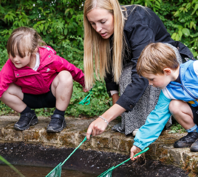 2 boys and a teacher playing with a pond