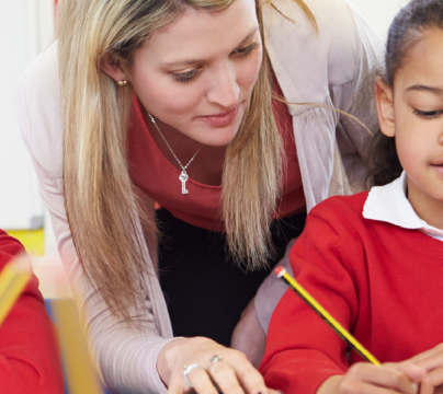 early years teacher with 2 children in red uniforms