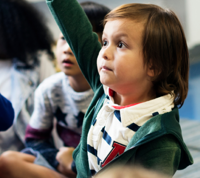 early years children in a group holding up hands