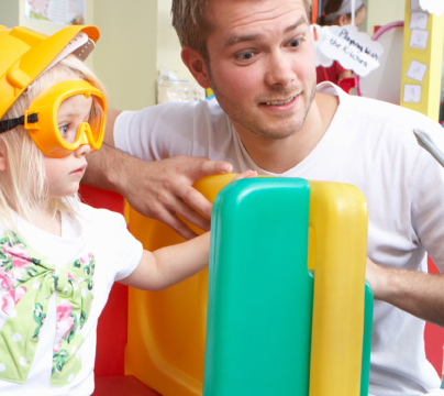man with 2 children playing in a classroom
