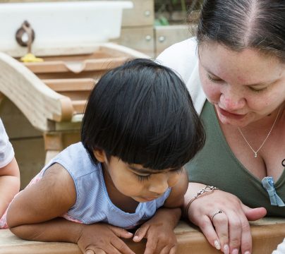 2 year olds with a teacher with a sandpit