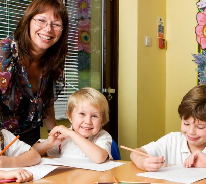 Teacher and children sitting around a school desk