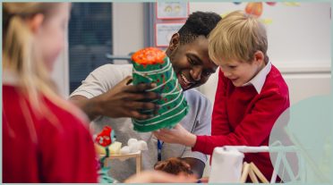 2children in red uniform playing with crafts with teacher