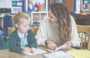 Child and teacher sitting at desk