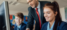 2 secondary pupils looking at laptop with teacher