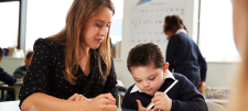 teacher and child who is writing