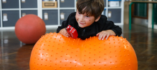 Boy on orange inflatable toy holding a toy bus