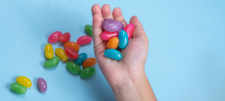 Hand holding large jelly-beans on blue background