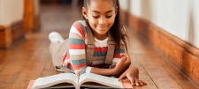 Girl reading book on floor