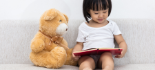 Early Years child reading to teddy