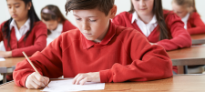 boys in red jumpers writing
