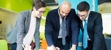 2 men and a woman looking at some paperwork
