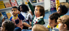 early years children in a group holding up hands