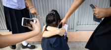 Hands and phones pointing at unhappy child with face hidden