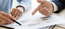 2 hands pointing at graphs on paper