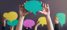 Lots of hands holding up cut-outs of speech bubbles